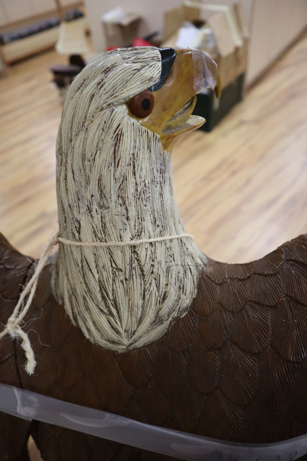 A carved and painted wood model of a Bald Eagle perched on a tree stump and a carved and painted wood hanging sign